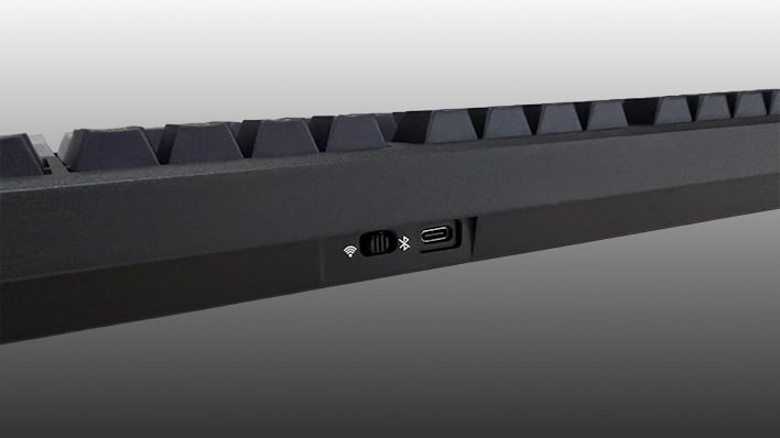 Closeup of the toggle on the back of the Epomaker Galaxy100 Lite keyboard, on a gray gradient background.