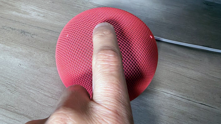 Tapping the top of the Google Home Speaker.