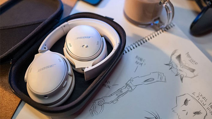 Bose QuietComfort 45 headphones folded up and in a case on a table.