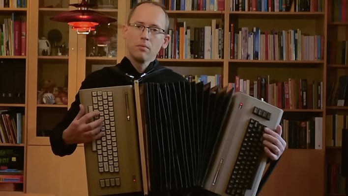 Engineer holding a custom-built accordion made from two Commodore 64 PCs.