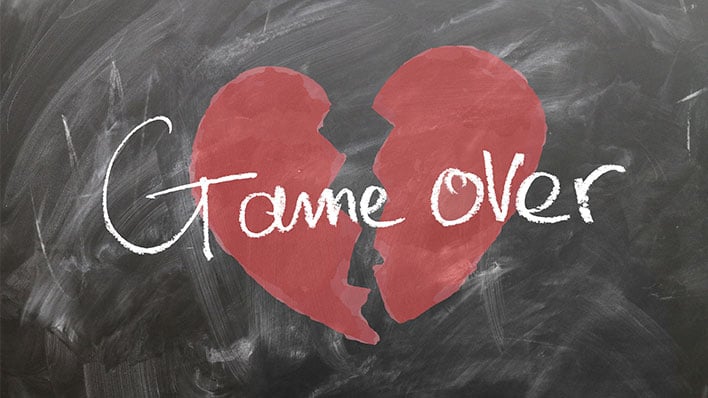 A chalkboard with a broken heart in red and the words "Game Over" in white written across it.
