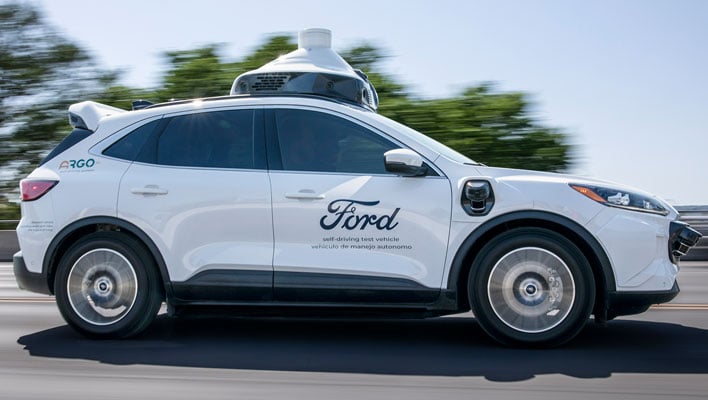 Side shot of a Ford autonomous test vehicle driving down a road.
