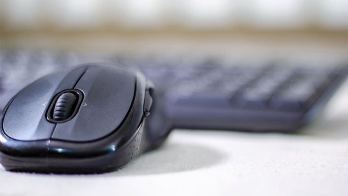 Closeup of a computer mouse in front of a blurred out keyboard.