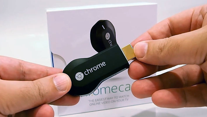 Holding a 1st Gen Google Chromecast dongle in front of its retail box.