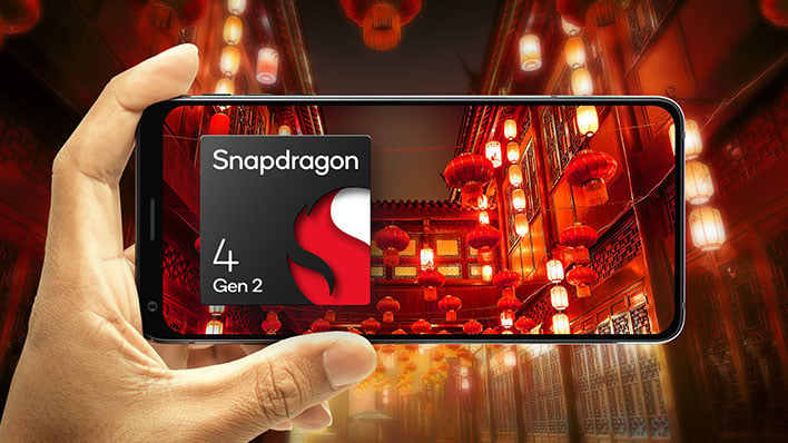 Holding a smartphone in front of a city background with a Snapdragon 4 Gen 2 image on the display.
