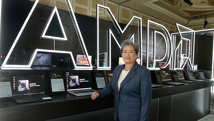 Dr. Lisa Su standing in front of a line of laptops and an AMD sign.