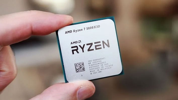Holding a Ryzen 7 5800X3D CPU.