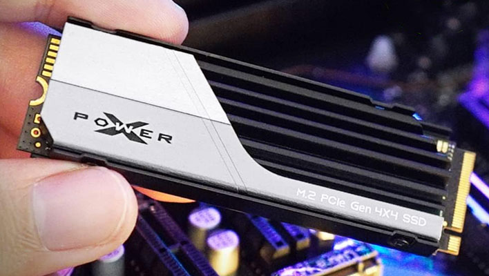 Hand holding a Silicon Power XS70 SSD over a motherboard.