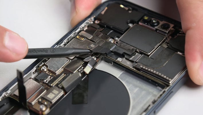 The inside of an iPhone 15 Pro Max being worked on with a plastic spudger.