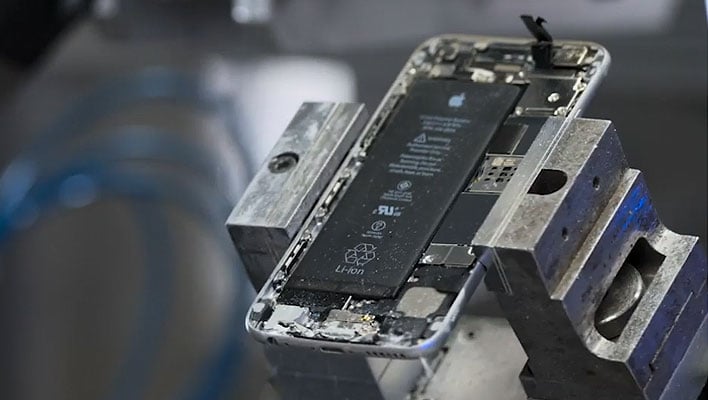 Machine holding a disassembled iPhone showing the battery inside.