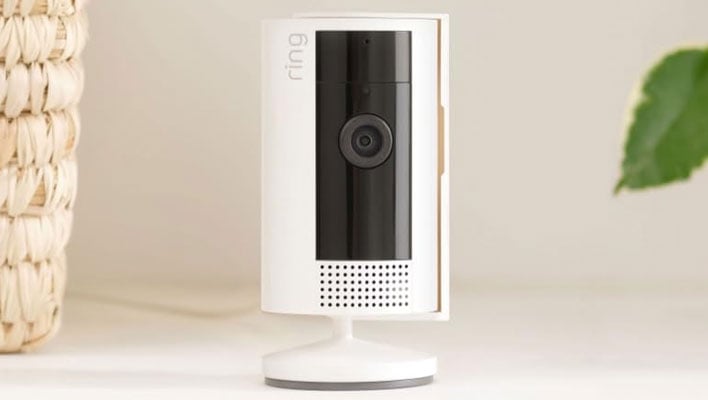 Ring INdoor Cam on a table next to a weaved basket and plant.