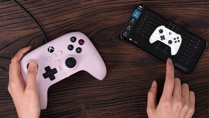8BitDo Ultimate Wired controller on a desk next to a smartphone.