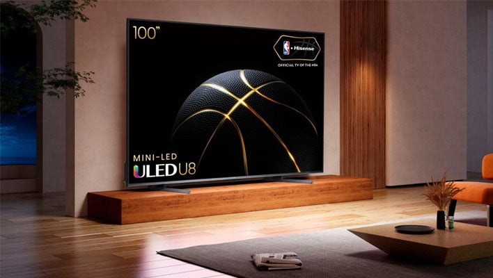 Hisense 100-inch U8K TV on a wooden step in front of a living room wall.
