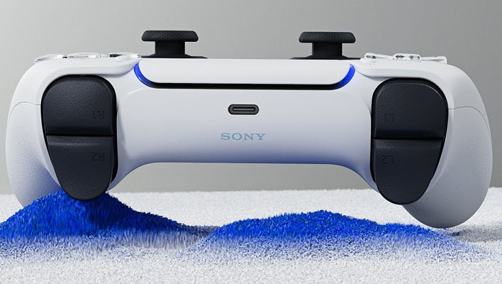 Top side of Sony's DualSense controller on a blue an white sandy surface.