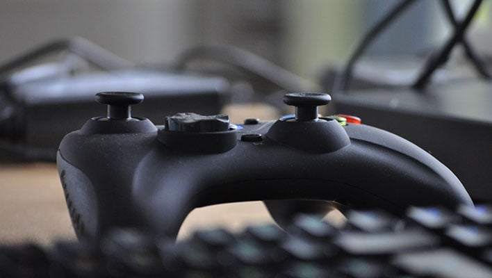 Closeup of a game controller sitting above a keyboard.