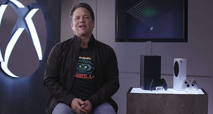 Microsoft's Phil Spencer sitting next to an Xbox Series X and Xbox Series S.
