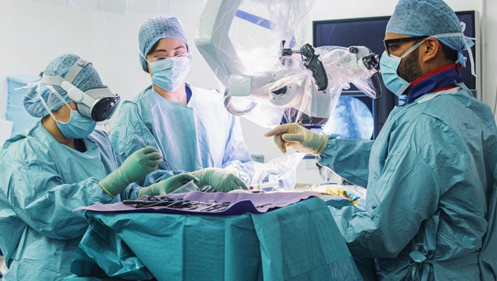 Surgical team prepping for surgery, with a scrub nurse wearing an Apple Vision Pro headset.