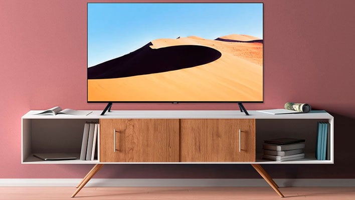 TV Samsung TU690T 4K su un piedistallo davanti a una parete rosata.