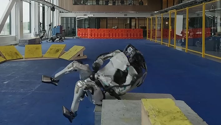 Boston Dynamics' Atlas robot falling down on a blue mat.