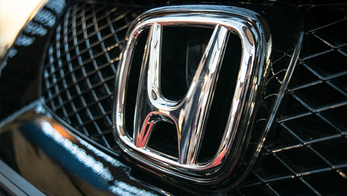 Closeup of a Honda badge on the front grill of a vehicle.
