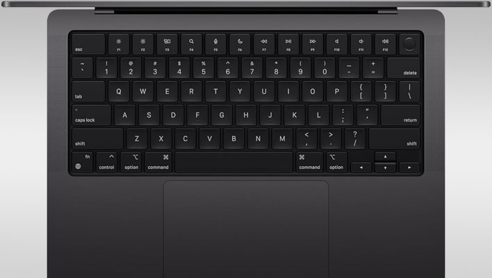 Apple MacBook Pro (top-down view focused on the keyboard) on a gray gradient background.