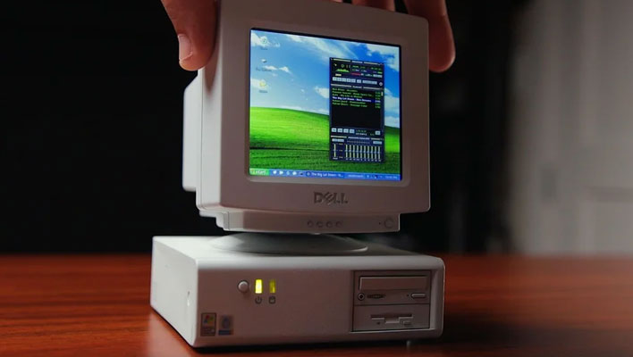 Hand reaching down to twist the monitor on a tiny 3D printed PC.