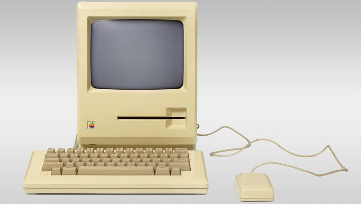 Apple Macintosh prototype with mouse on a gray gradient background.