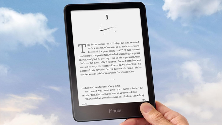 Hand holding a Kindle Paperwhite in front of a cloudy sky.