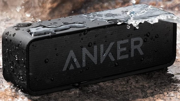 Anker Soundcore speaker on a rocky surface and doused with water.