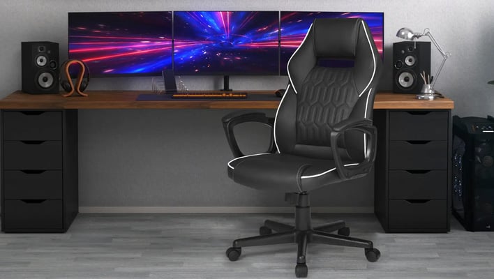 Insignia Essential gaming chair positioned in front of a PC gaming setup.