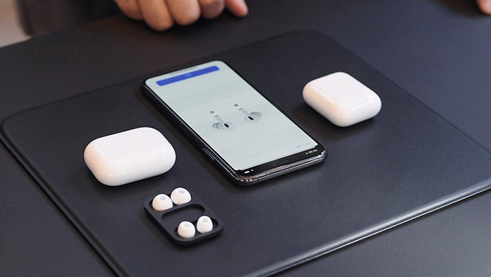 Apple AirPods and iPhone on a black mat.