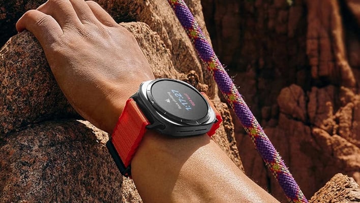 Samsung Galaxy Watch Ultra on an wrist that is scaling a rocky mountain.