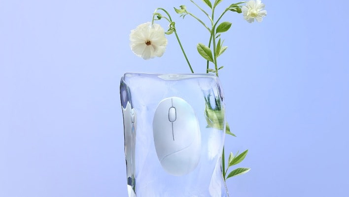 ASUS Fragrance Mouse in a ice-looking enclosure next to flowers.