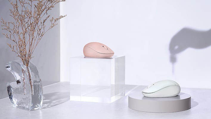 Two ASUS Fragrance Mouse models (MD101) on pedestals next to a vase. On the wall, there's a shadow of a hand adding essential oil to one of the mice.