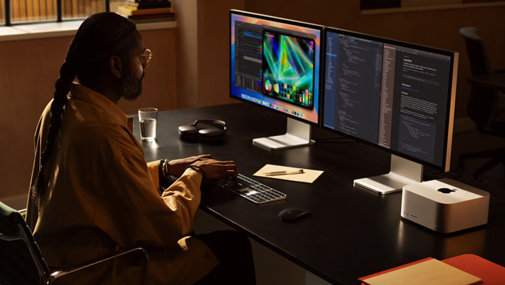 Person sitting at a desk with a Mac Studio connected to dual monitors.