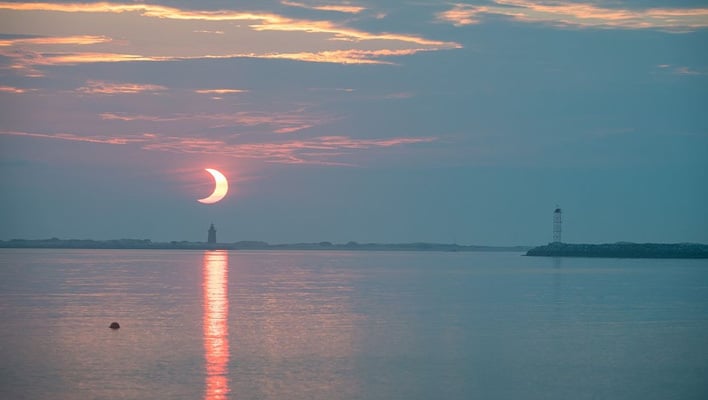 Partial solar eclipse over a body of water.