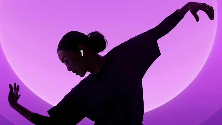 Silhouette of a woman wearing Apple AirPods in front of a pink-themed background.