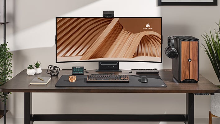 Corsair One i600 PC de jeu avec garniture en bois sur un bureau à côté d'un moniteur.