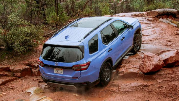 A blue Honda Pilot navigating rocky terrain.