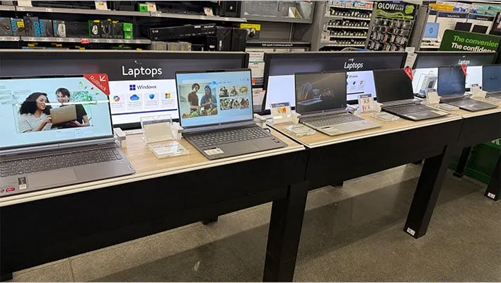 Row of laptops on a store shelf.