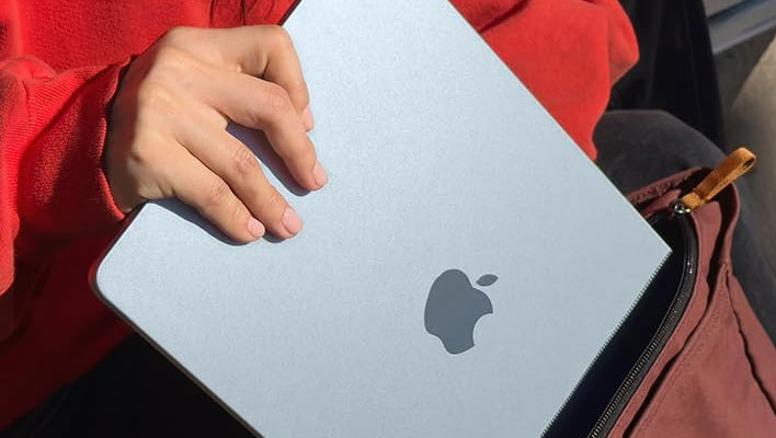 Apple MacBook Air being shoved into a bag.