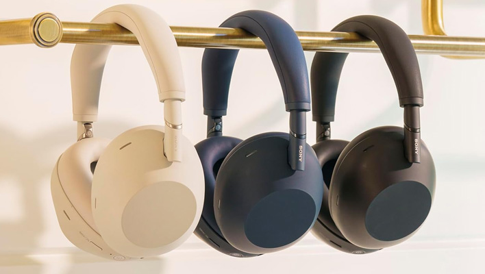 Three sets of Sony WH-1000MX6 headphones hanging from a bar.