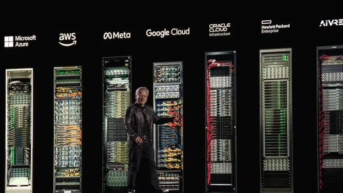 NVIDA CEO Jensen Huang on stage in front of racks for companies like Microsoft, AWS, Meta, Google, Oracle, and others.