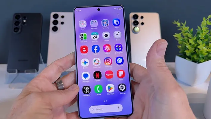 Samsung Galaxy S26 Ultra being held in front of other Galaxy smartphones.