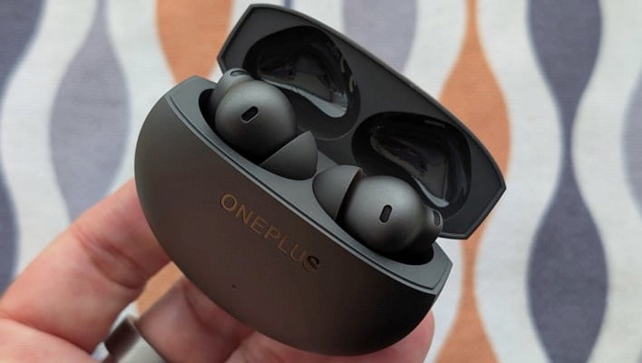 OnePlus Buds 4 in a charging case, in a hand.