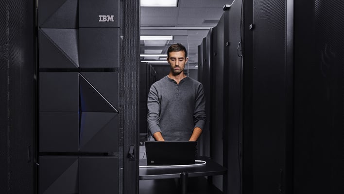 User on a laptop next to IBM's mainframe.