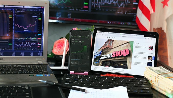 Laptops displaying stock trackers and a GameStop article.