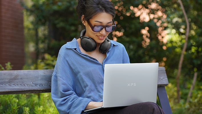 Person on a park bench with a Dell XPS 13 laptop.