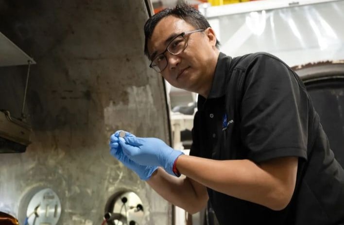 Yi Lin, SPEARS testing and research lead at NASA Langley, holds one of the small coin-cell batteries that had just undergone thermal vacuum testing